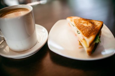 ahşap bir masa üzerinde sandviç ve Kupası kahve