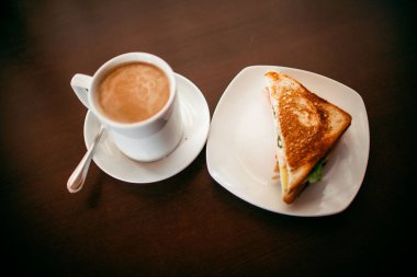 ahşap bir masa üzerinde sandviç ve Kupası kahve