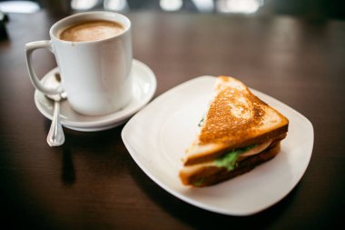 ahşap bir masa üzerinde sandviç ve Kupası kahve