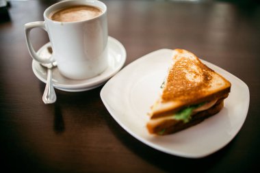 ahşap bir masa üzerinde sandviç ve Kupası kahve