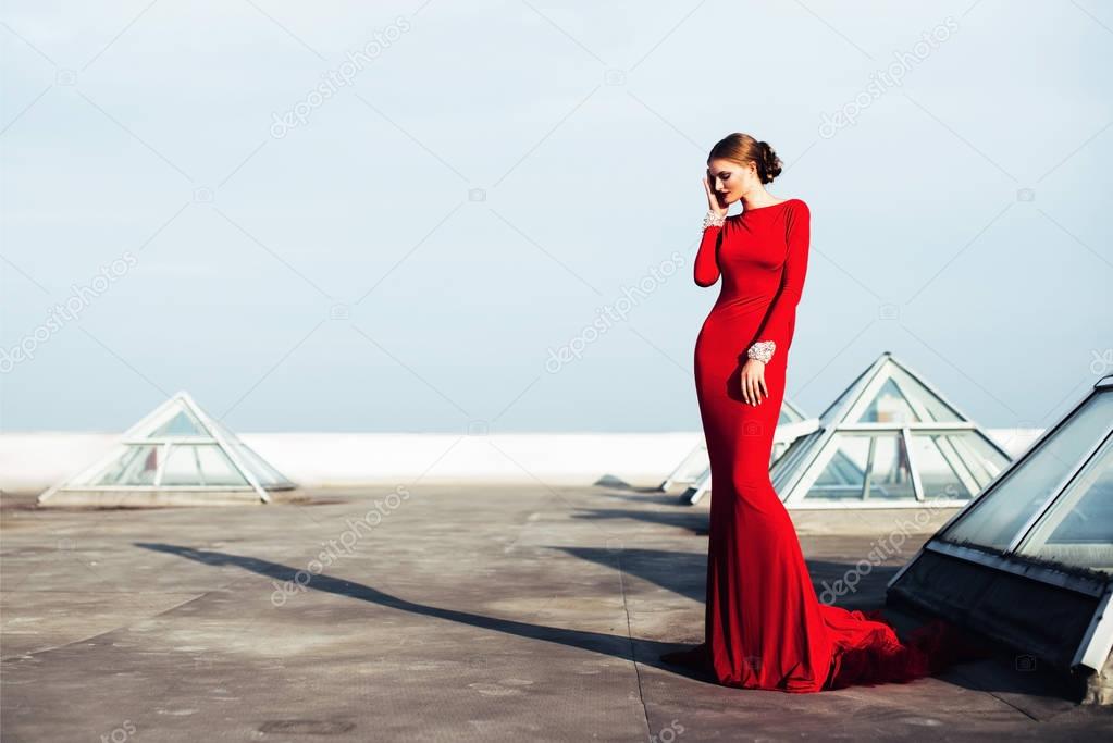 Gorgeous elegant woman in red long dress with diamonds on the roof