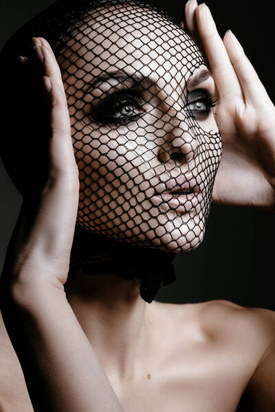 Fashion portrait of Beautiful sexy woman with black veil on face on black background