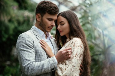 Romantik çift, gelin ve damat bahçedeki bitkilerin arka planına karşı serada poz veriyorlar. Reklam alanı