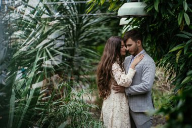 Romantik çift, gelin ve damat bahçedeki bitkilerin arka planına karşı serada poz veriyorlar. Reklam alanı