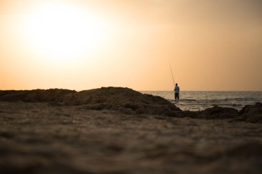 Bir adam günbatımı çerçevede bir denizde Balık tutma