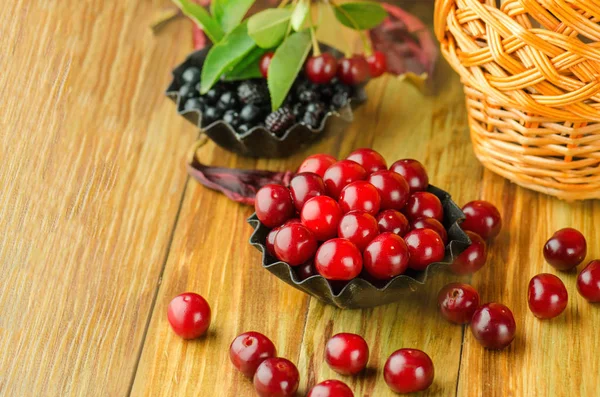 Taze kiraz ve ahşap üzerine siyah plaka üzerinde yaban mersini