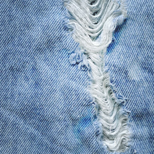 Hole and threads on denim jeans — Stock Photo, Image
