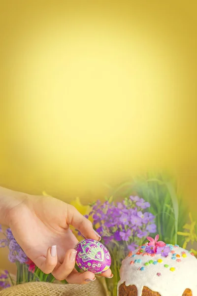 Påskägg i en hand på en bakgrund av påsk dekoration och våren blommor. Påsk frukost koncept. — Stockfoto