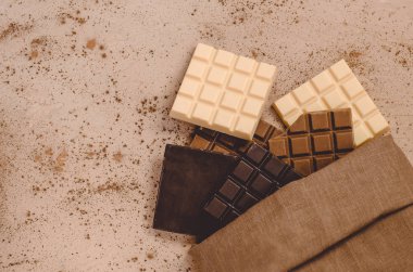 Tahta arka planda çeşitli çikolata parçalarının üst görüntüsü