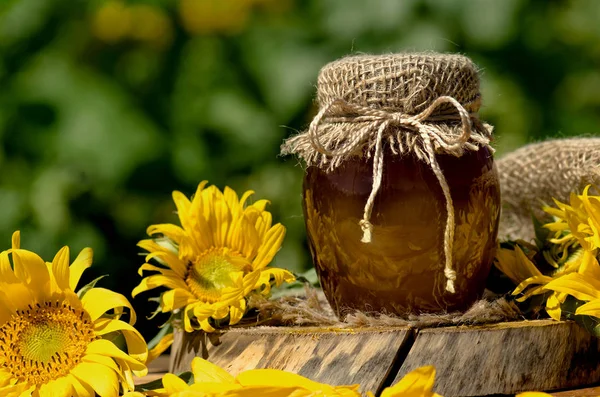 Miel en el campo de flores silvestres. Tarro de miel fresca en el campo de flores silvestres — Foto de Stock