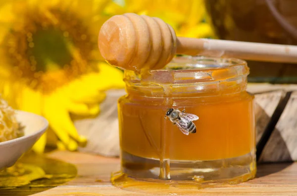 Miel en frasco de vidrio con abeja volando — Foto de Stock