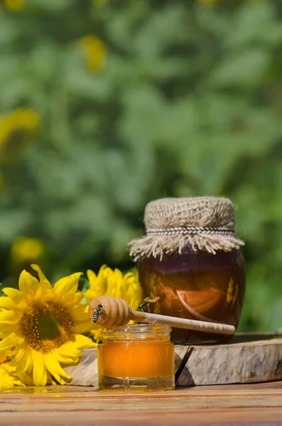 Miel en frasco de vidrio con abeja volando — Foto de Stock