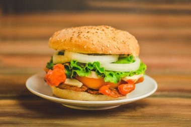 Ev yapımı hamburgerin yakın çekimi. Et ve peynirli hamburger. Pastırmalı, peynirli, marullu ve domatesli büyük lezzetli bir çizburger. Metin için boşluk.