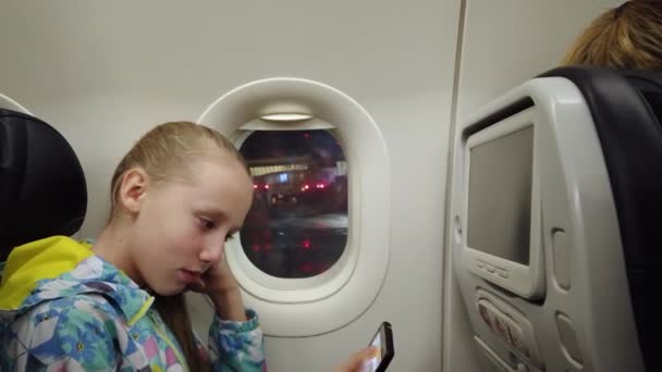 Дівчина з мобільним телефоном у літаку . — стокове відео