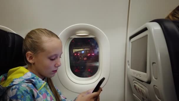 Ragazza con un telefono cellulare in un aereo. — Video Stock