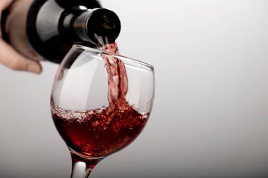 Kırmızı şarap şarap cam içine beyaz zemin üzerine dökülür varlık