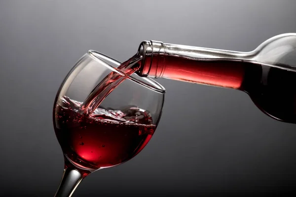 Rött vin hälla i ett glas som isolerade — Stockfoto