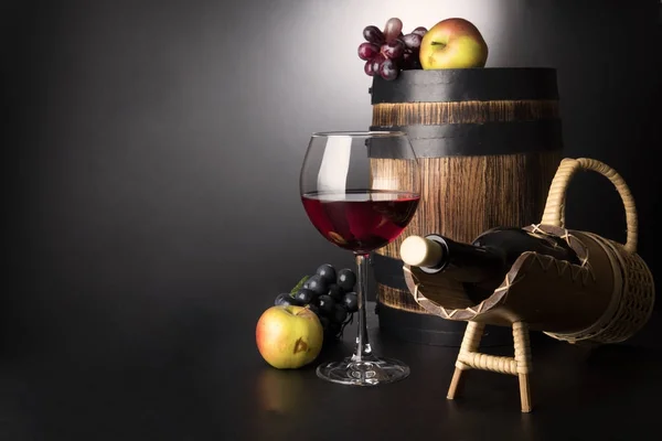 Rött vin glas med flaska i sraw prop och gamla trätunna omgiven av frukter: vine och äpplen — Stockfoto