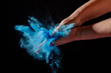 Holi Festivali renkli kuru boya tutan eller closeup çekim. Mavi renkli sıçrama boya.