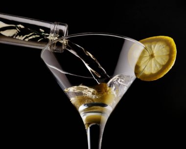 Soğutulmuş cam zeytin ve limon ile süslenmiş siyah arka plan üzerine klasik martini. Yakın çekim.