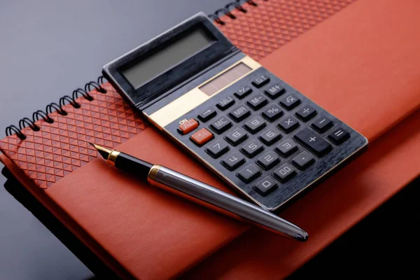 A fountain pen, calculator and cheque book or note book