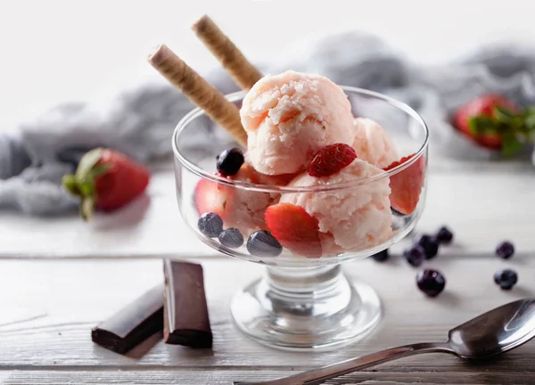 Αρκετές μπάλες παγωτό Φράουλα με γκοφρέτα, φράουλα και μπλε μούρο σε ποτήρι ενάντια σε λευκό ξύλινο τραπέζι. Καλοκαιρινό φόντο. — Φωτογραφία Αρχείου