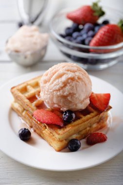 Çilekli dondurma, yaban mersini, çilek ve sos kepçe ile waffle.
