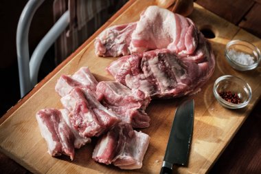 Çiğ Domuz kaburga bir ahşap kesme tahtası, mutfak bıçağı, tuz, baharat ve havlu.