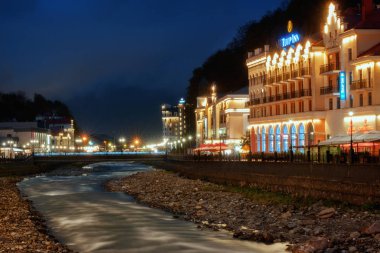 Rosa Khutor, Rusya Federasyonu - 22 Nisan 2018: Tulip Inn Hotel nehrin karşı tarafında dan gece görünümü.