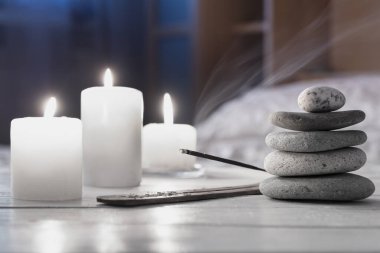 Rahatla, evde meditasyon. Zen taşı piramidi, yanan mumlar, beyaz ahşap tütsü. Rahatlama kavramı..