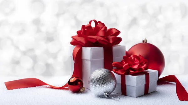 Presente de Natal ou Ano Novo, cartão de saudação. Duas caixas de presente com fita vermelha ao lado de várias bolas de Ano Novo no fundo branco . — Fotografia de Stock