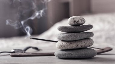 Rahatlama ya da meditasyon kavramı. Zen taşı piramidi, yanan tütsü çubuğu, yatak odası içi..