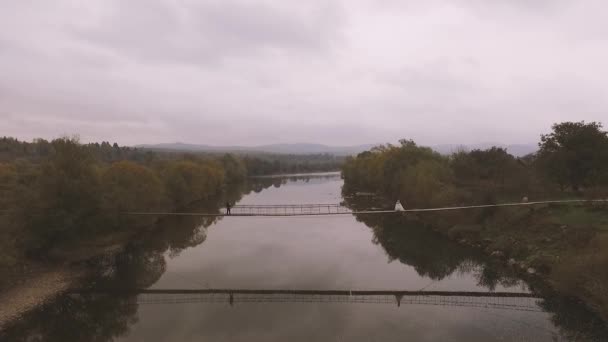 Luftbild. Liebespaar auf einer Holzbrücke in den Bergen — Stockvideo