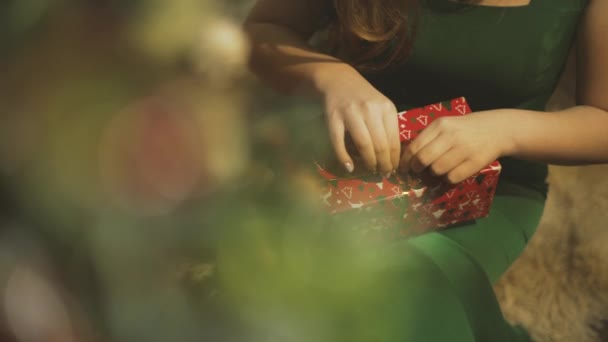 Дівчина розпаковує новорічний подарунок — стокове відео