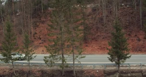 Белый автомобиль едет по горной дороге — стоковое видео