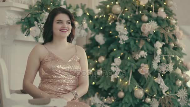 Mujer joven cerca del árbol de Navidad y desempaca regalos — Vídeos de Stock