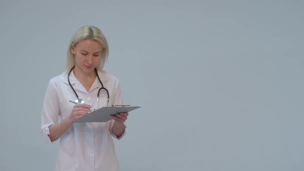 Πορτρέτο του μια γυναίκα γιατρό με άσπρο παλτό και στηθοσκόπιο χαμογελώντας ψάχνει σε κάμερα — Αρχείο Βίντεο