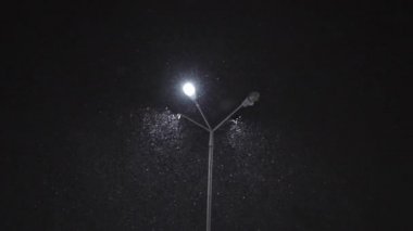 Gece bir sokak lambası yakınındaki düşen kar