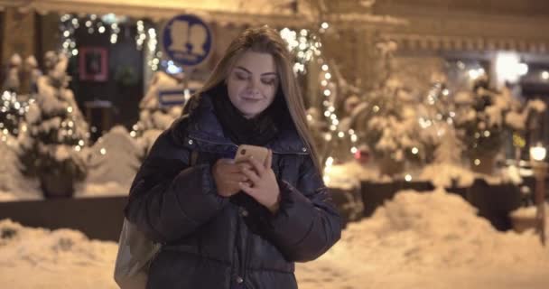 Mujer usando teléfono móvil durante un paseo por las calles de la ciudad nocturna — Vídeo de stock