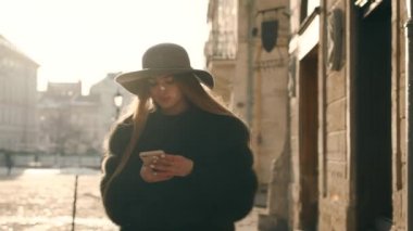 Genç kadın bir gri şapka ve uzun saç smartphone ile sms yazıyor