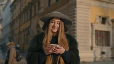 Kalabalık şehir sokak ayakta ve mesaj attığın için telefonunu kullanarak gri şapkalı kadın