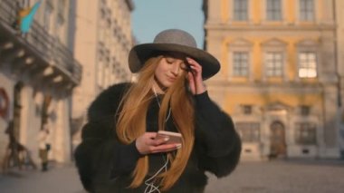 Genç kadın bir gri şapka ve uzun saç smartphone iletişim kurar.