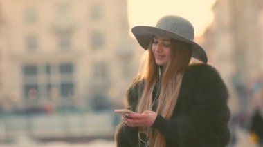 Parlak güneş ışığı altında çok güzel genç kadın telefonunu kullanır