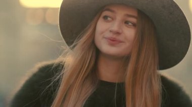 Gri şapkalı bir çekici genç kadın tatlı sağ ve gülümseme kameraya doğru görünüyor