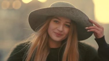 Gri şapkalı bir çekici genç kadın tatlı sağ ve gülümseme kameraya doğru görünüyor