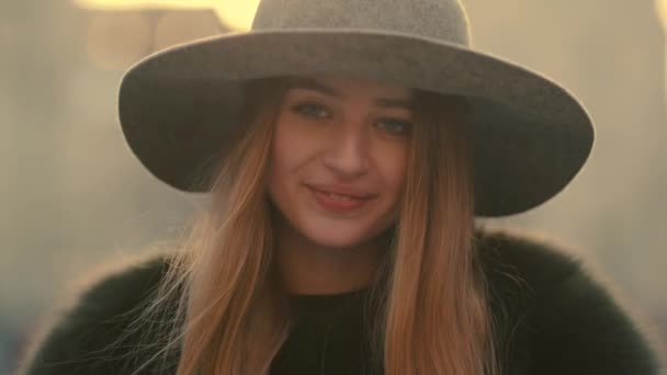 Glamorous young woman in a gray hat charmingly looks right and smile towards the camera — Stock Video