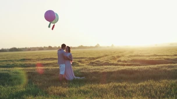 Loving para stojący w polu z helem kolorowe kulki — Wideo stockowe