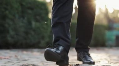 Siyah ayakkabılı bir adam öne çıkıyor ve dışarı çıkıyor. Yerde yürümek, erkek deri ayakkabılarının yakın görüntüsü.