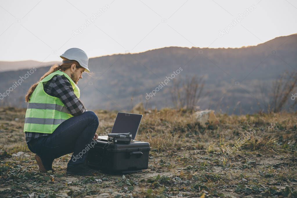 The engineer in the helmet works at the factory with an laptop. Creation of new technologies, production development. Industrial Engineer in Hard Hat Uses Touchscreen Laptop