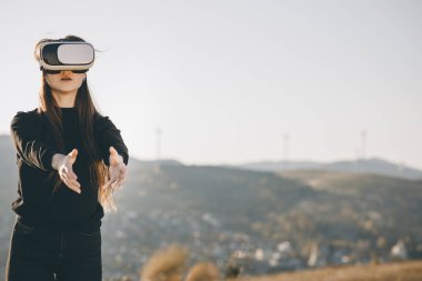 VR gözlükleriyle oyun oynayan güzel genç bir bayan. Güzel bir kadın modern sanal gerçeklik gözlüğü kullanarak bir şeye dokunuyor. Gelecek şimdidir..